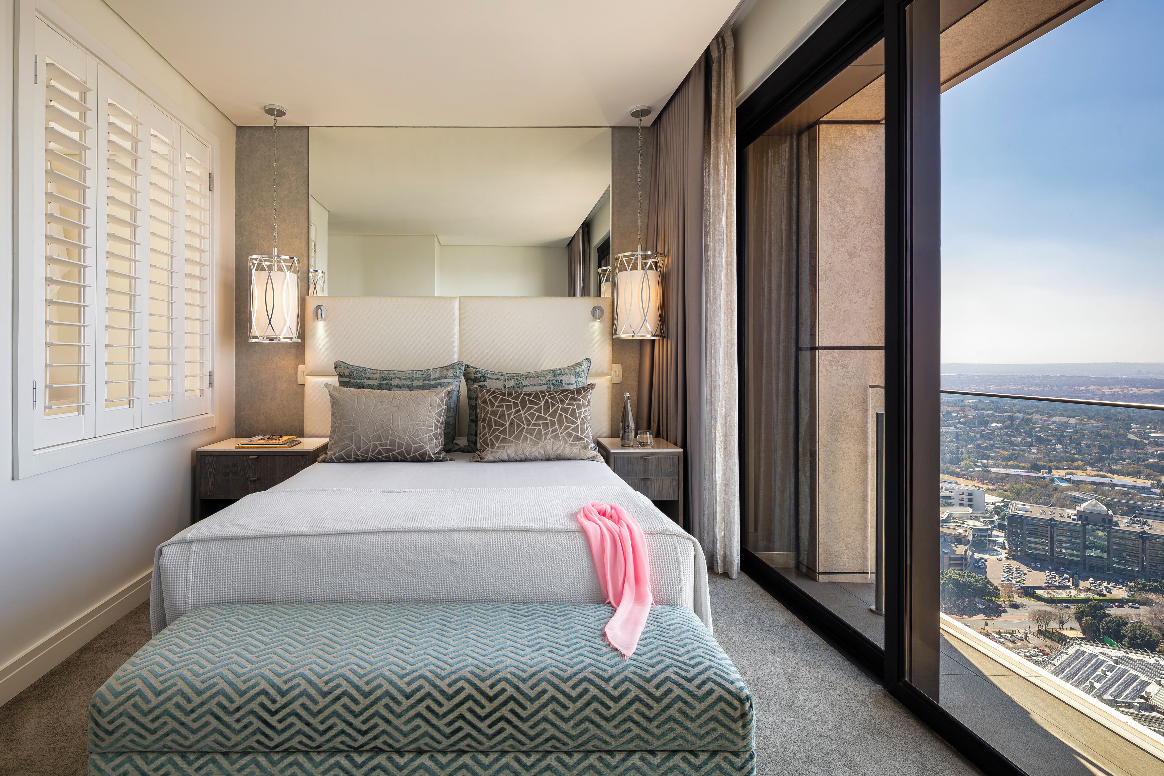 A modern hotel room with a large bed, a view of the city, and a balcony.