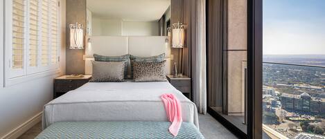 A modern hotel room with a large bed, a view of the city, and a balcony.