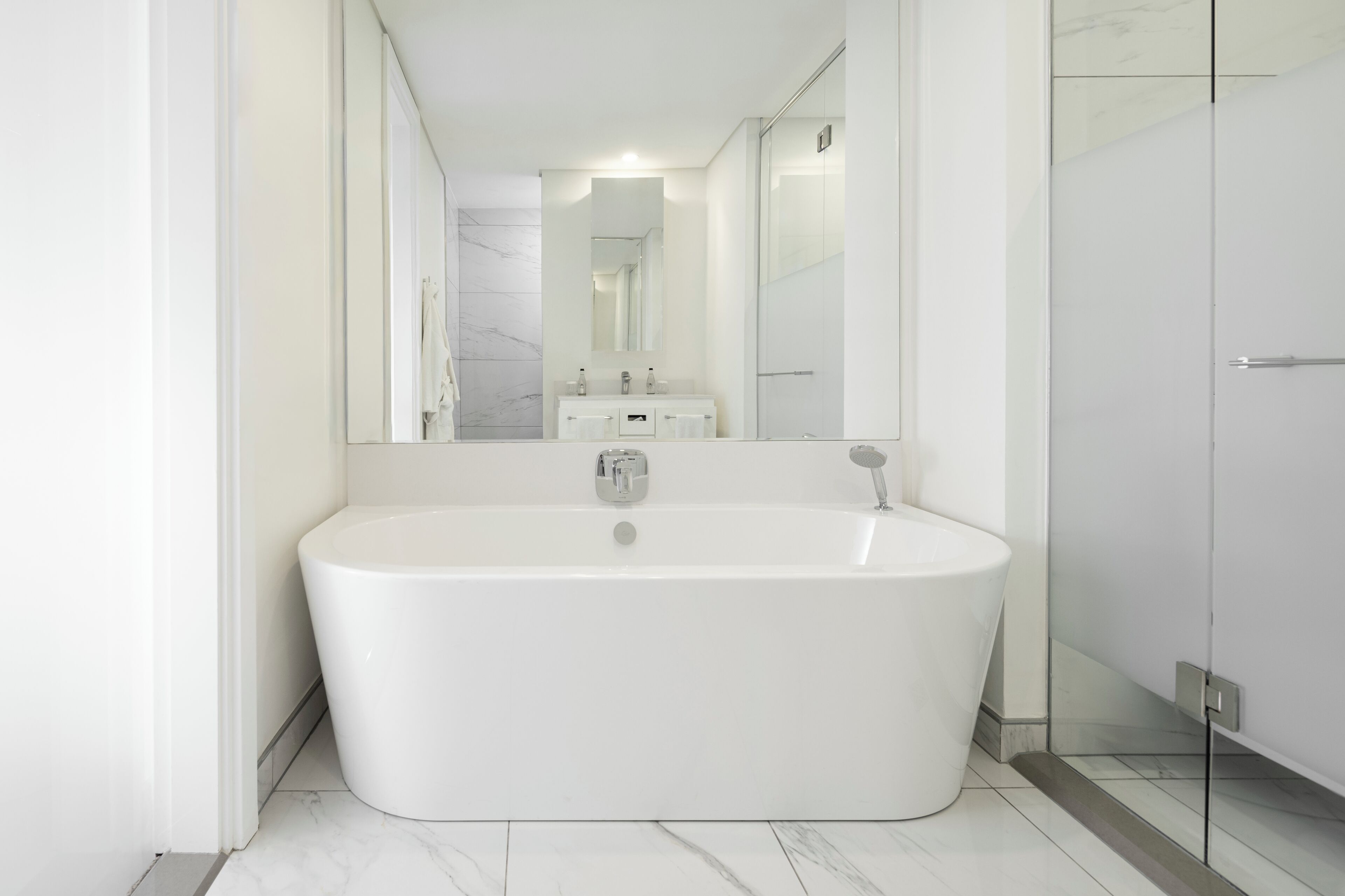 A modern bathroom with a freestanding bathtub, a large mirror, and a glass shower enclosure.