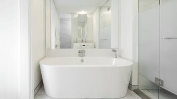 A modern bathroom with a freestanding bathtub, a large mirror, and a glass shower enclosure.