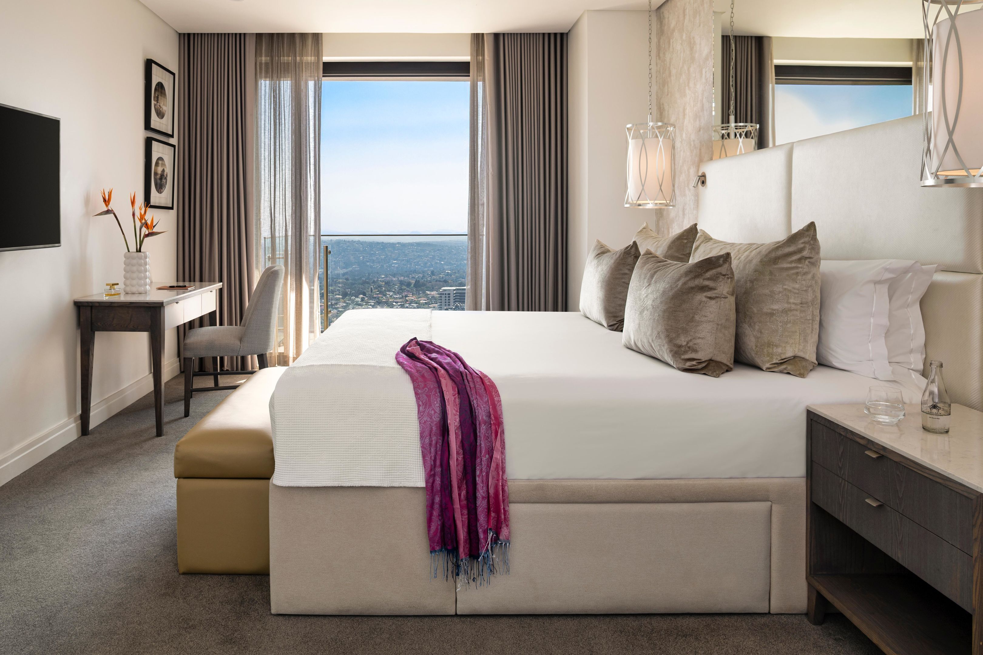 Une chambre d’hôtel moderne avec un grand lit, un bureau et une vue sur la ville.