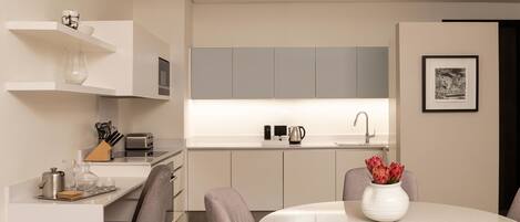 Une cuisine moderne avec des meubles blancs, une table à manger avec des chaises et un luminaire suspendu.
