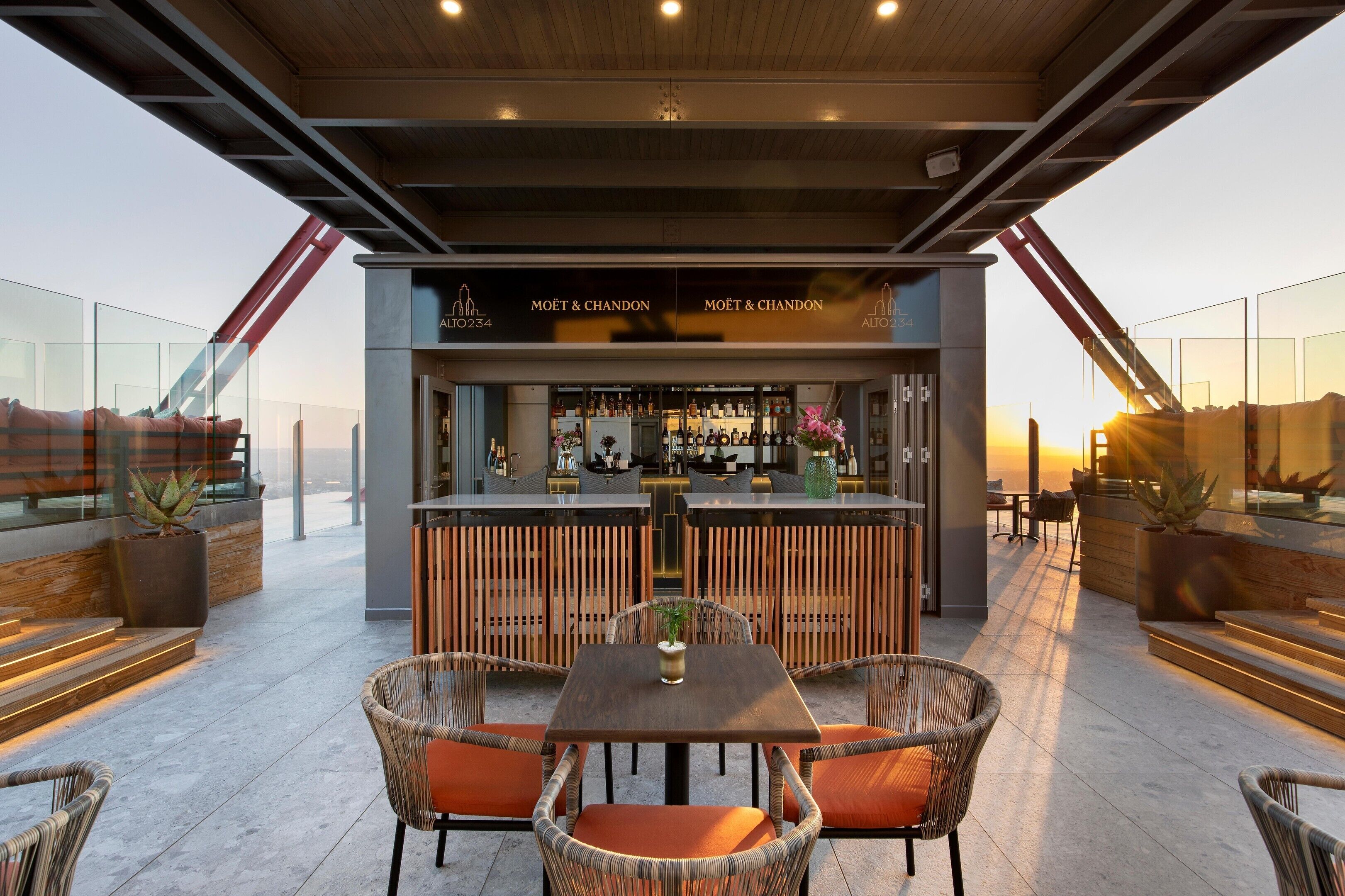 Un espace bar extérieur au design moderne, comprenant un comptoir, des sièges et une vue sur le paysage urbain.