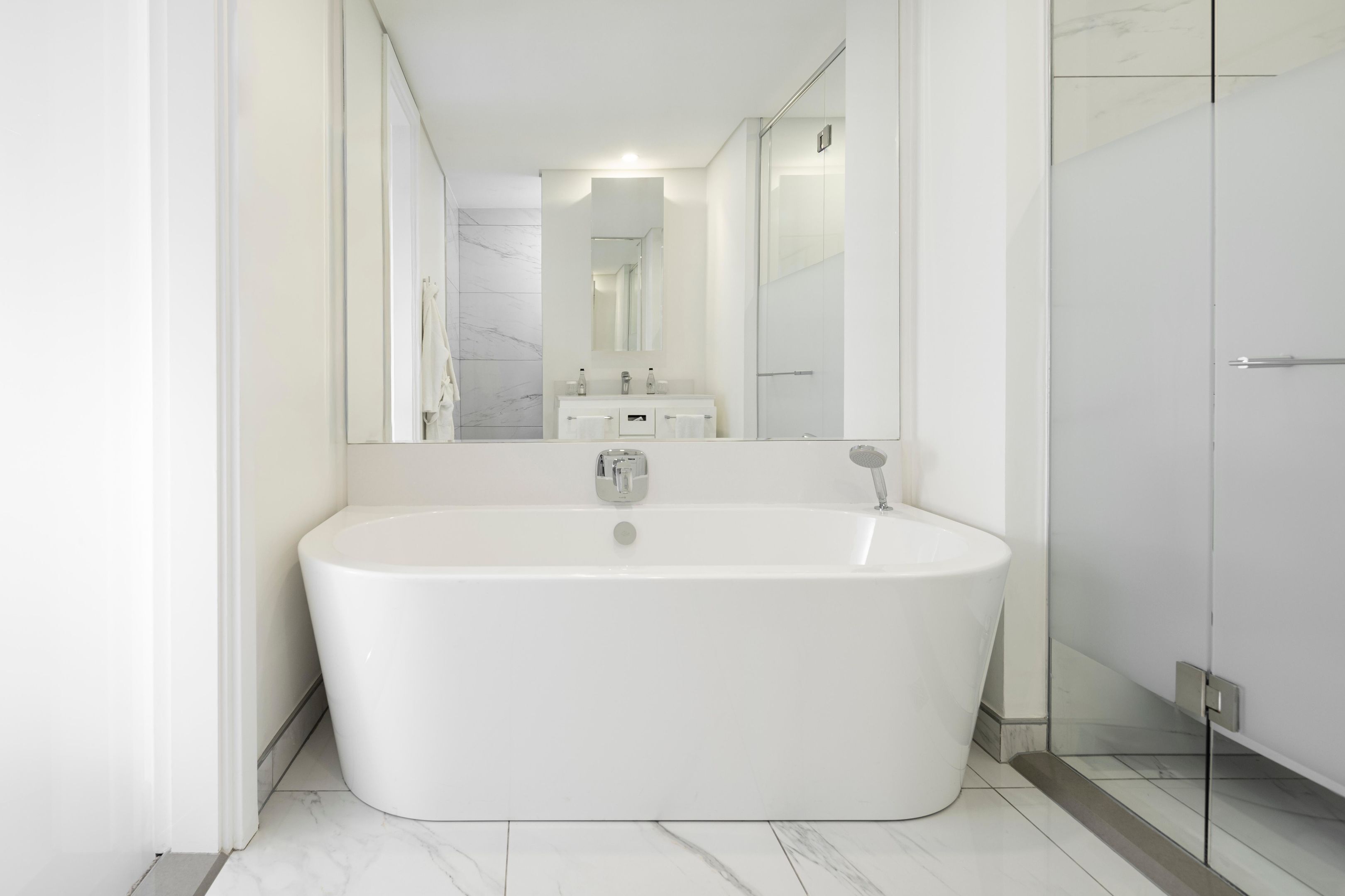 A modern bathroom with a freestanding bathtub, a large mirror, and a glass shower enclosure.