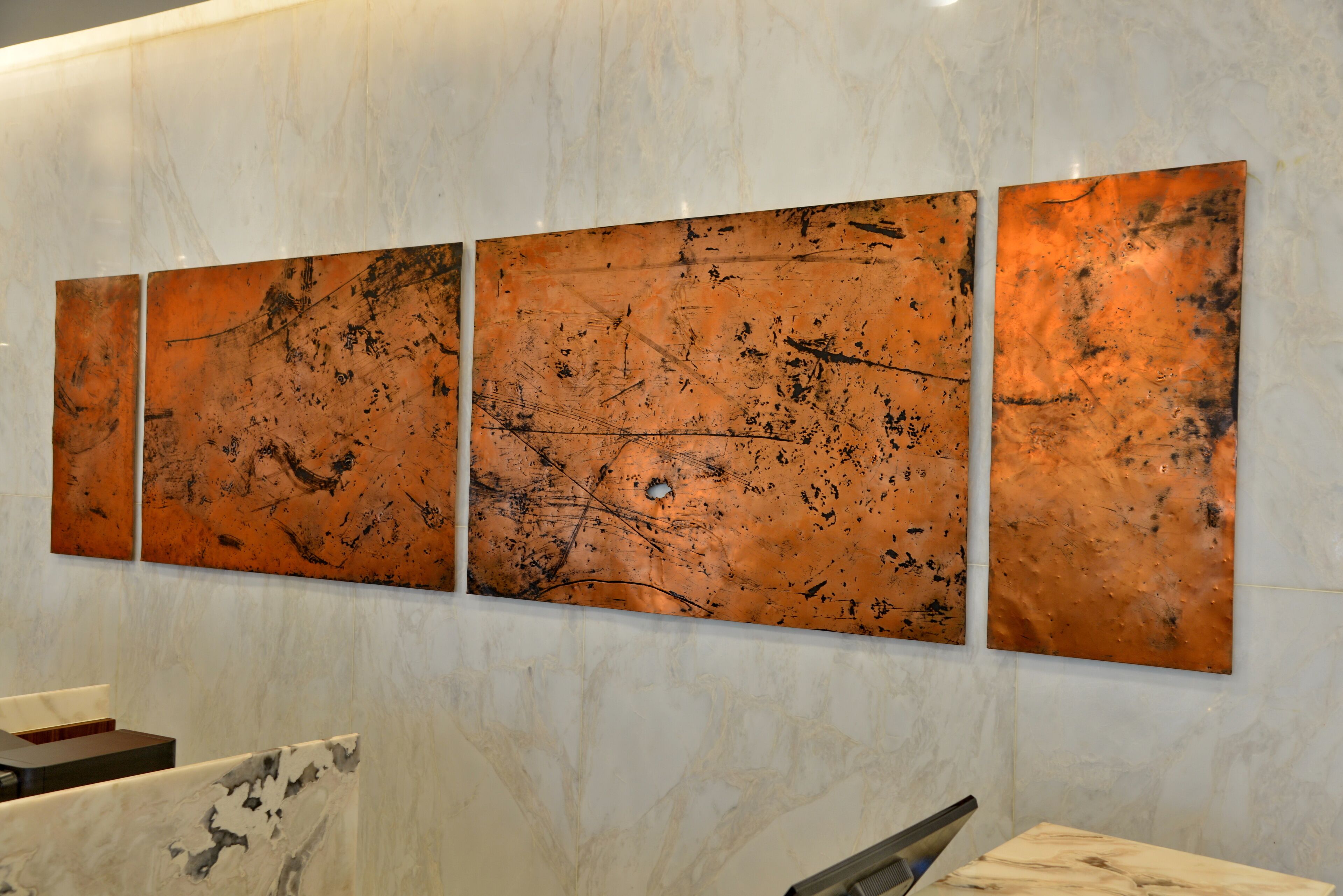 Una pared con tres grandes paneles metálicos abstractos.