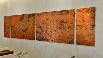 Un mur orné de trois grands panneaux métalliques aux motifs abstraits.