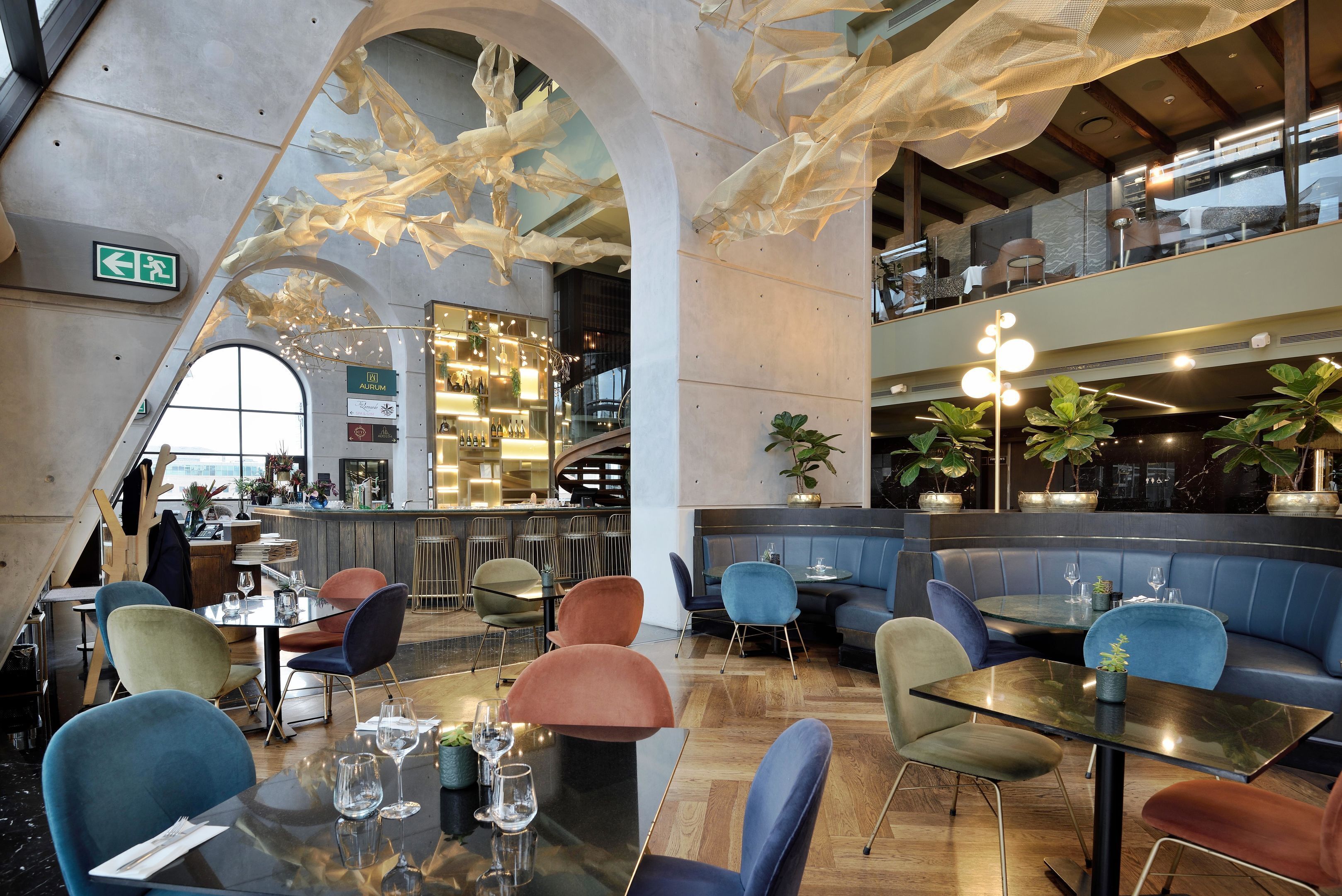 A modern restaurant with high ceilings, unique ceiling art, and a variety of seating options including booths and tables.