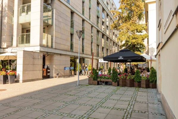A courtyard with a café, outdoor seating, and a building with multiple floors and balconies.