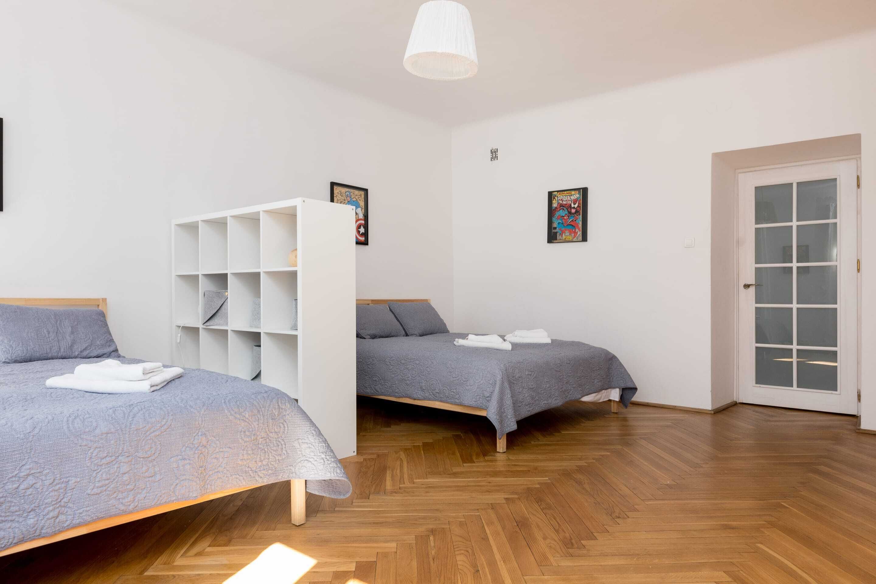 A room with two beds, a white wardrobe, and a door.