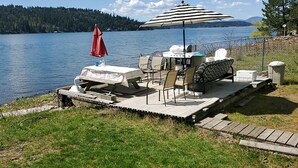 Een vastgemaakt bootje met een barbecue, zitplaatsen en een rode parasol.