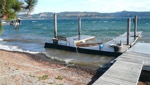 Een houten steiger die uitsteekt in een rustig wateroppervlak, met een bankje en een bordje, omgeven door een natuurlijke omgeving.
