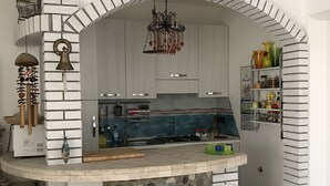 Une cuisine dotée d’un plan de travail en pierre, de tabourets de bar blancs et d’un lustre suspendu.