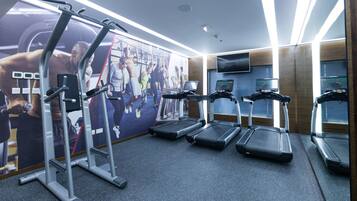 A gym with treadmills, a weight machine, and a large motivational poster on the wall.