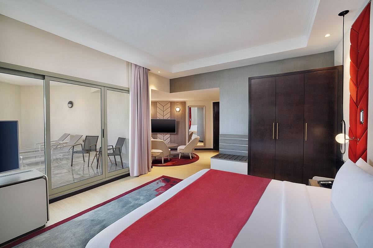 A hotel room with a large bed, a TV, a desk, and a seating area with chairs and a table.