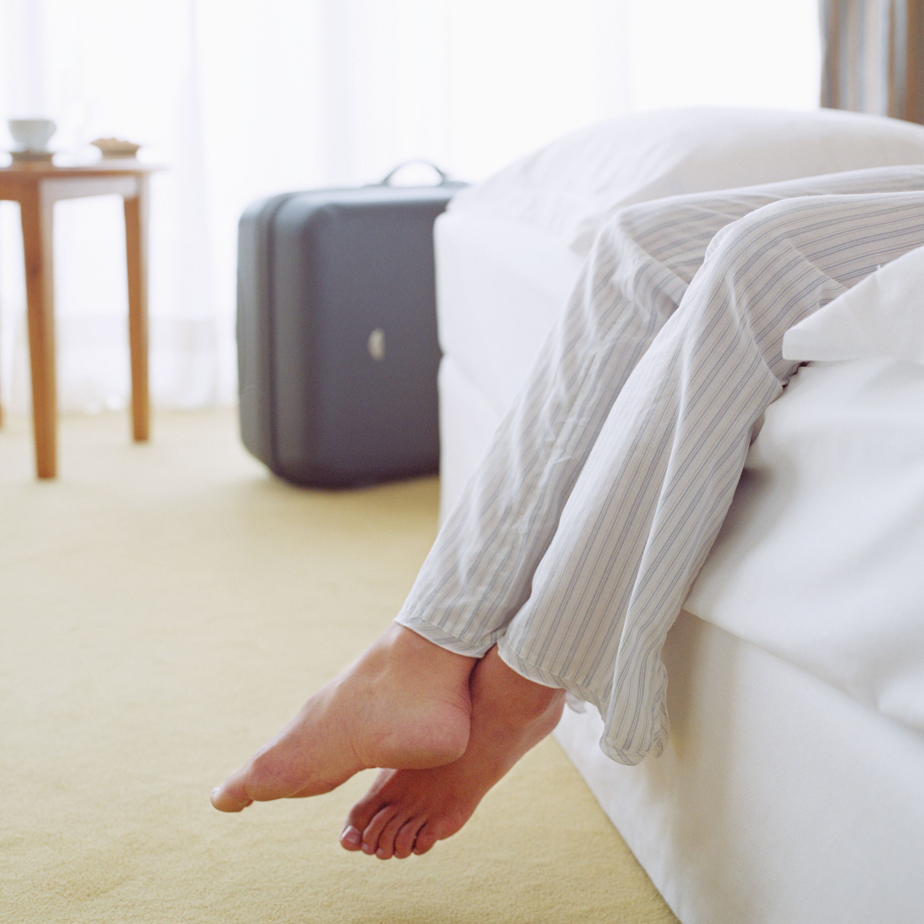 A bed with a suitcase in the background.