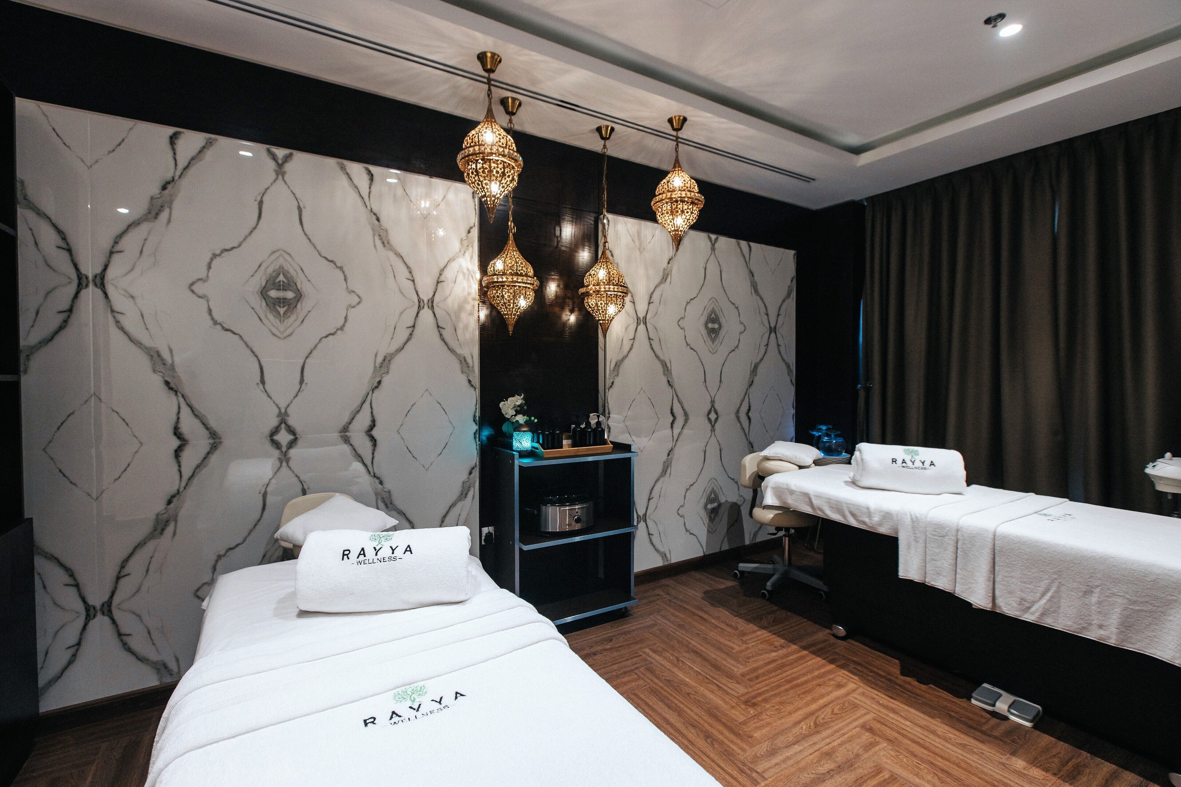 Una sala moderna para el bienestar, con una cama, mesa de masaje e iluminación decorativa colgante.