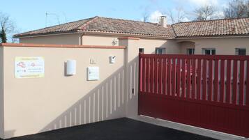 A hotel entrance with a red gate, a signboard with contact information, and a number '10' on the wall.