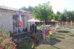 Een terras met een tafel, stoelen, een vlag en plantenpotten.