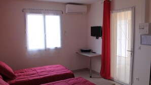Quarto com duas camas, janela com cortina, ar condicionado, televisão na parede e porta com janela de vidro deslizante.