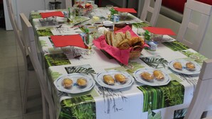Mesa posta com pratos de comida, um cesto de pão e diversos acompanhamentos.