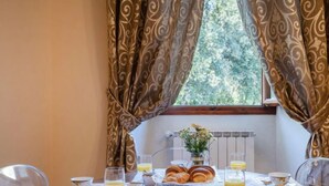 Une table de petit-déjeuner dressée avec des croissants, du jus d’orange et un vase rempli de fleurs.