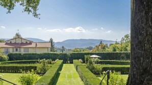 Un jardin bien entretenu, avec un chemin central menant à un bâtiment doté d’un toit rouge.