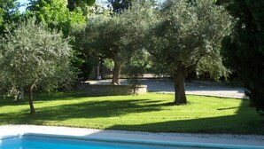 A swimming pool with a stone border, surrounded by a well-maintained lawn and trees. - The Temple at Solebello (Morro D' Alba)