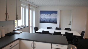 Eine moderne Küche mit weißen Schränken, einer schwarzen Arbeitsplatte und einem Essbereich mit weißem Tisch und schwarzen Stühlen.