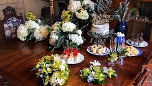 Una mesa de comedor de madera con centros de mesa florales, un pastel con el decorado 'Mr & Mrs' y diversos alimentos.