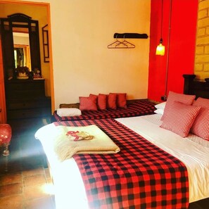 A hotel room with a checkered bedspread, red pillows, and a hanging light fixture. - Mi Casa Es Tu Casa Inn (Chiquinquirá)