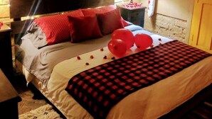 Un dormitorio con cabecera estampada en ladrillos, cama con ropa de cama roja y blanca, y globos sobre la cama.