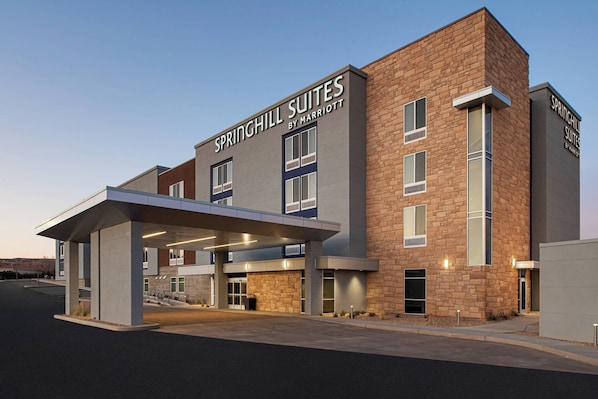 A modern hotel with a brick facade, large windows, and a covered entrance area.