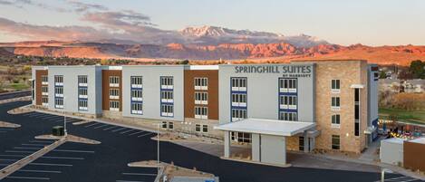 A hotel named Springhill Suites by Marriott with a parking lot and a mountain backdrop.