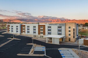 Un hotel llamado Springhill Suites by Marriott con un estacionamiento y montañas al fondo.