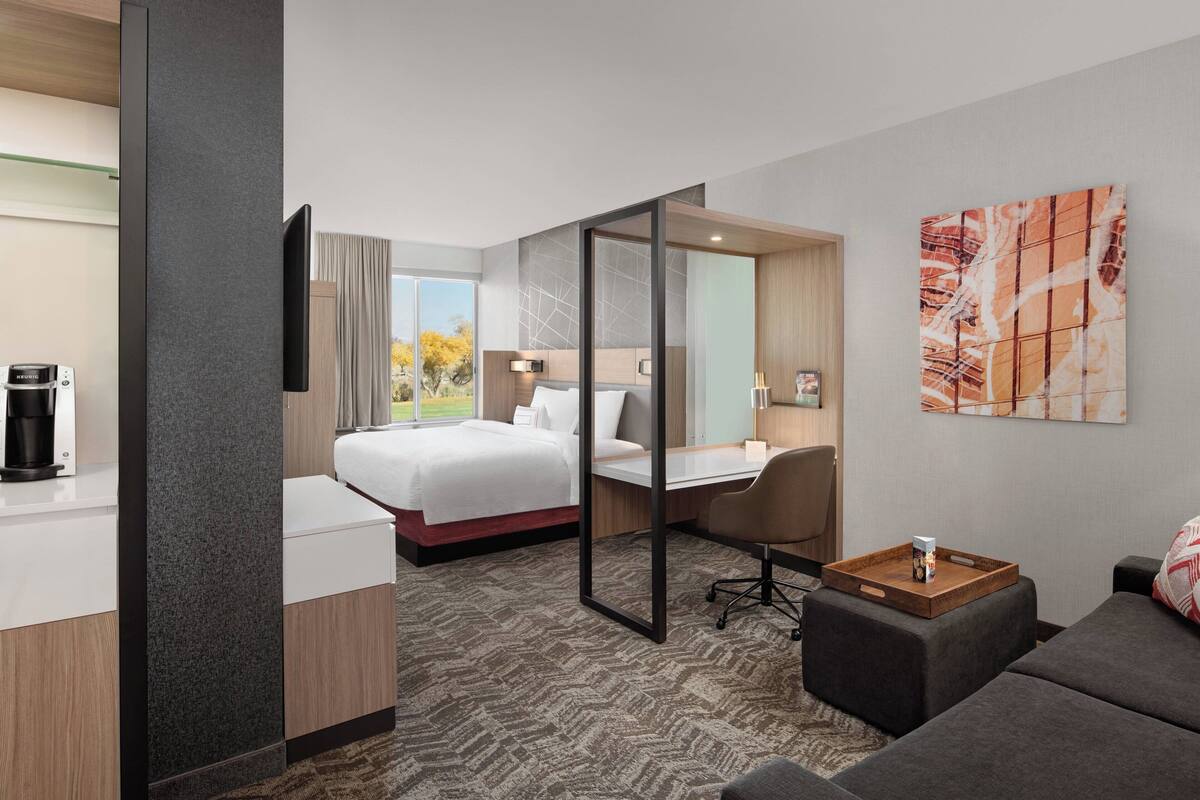 A hotel room with a bed, desk, and seating area.