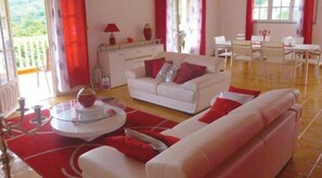 Ein gemütliches Wohnzimmer mit einem weißen Sofa, roten Akzenten und einem Glastisch.