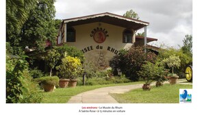 A building with a sign reading "Le Musée du Rhum" surrounded by lush greenery and potted plants. - Villa O Jardin d'Alice (Deshaies)