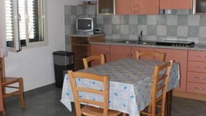 Une cuisine compacte avec une table à manger, des chaises en bois et un petit téléviseur.