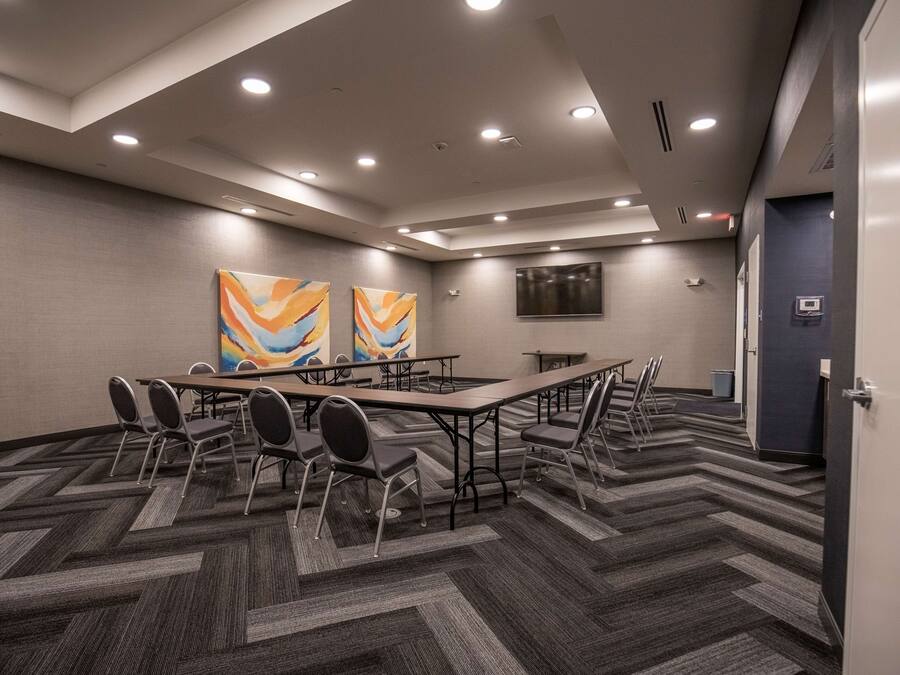 A conference room with a large table, chairs, and two abstract paintings on the wall.