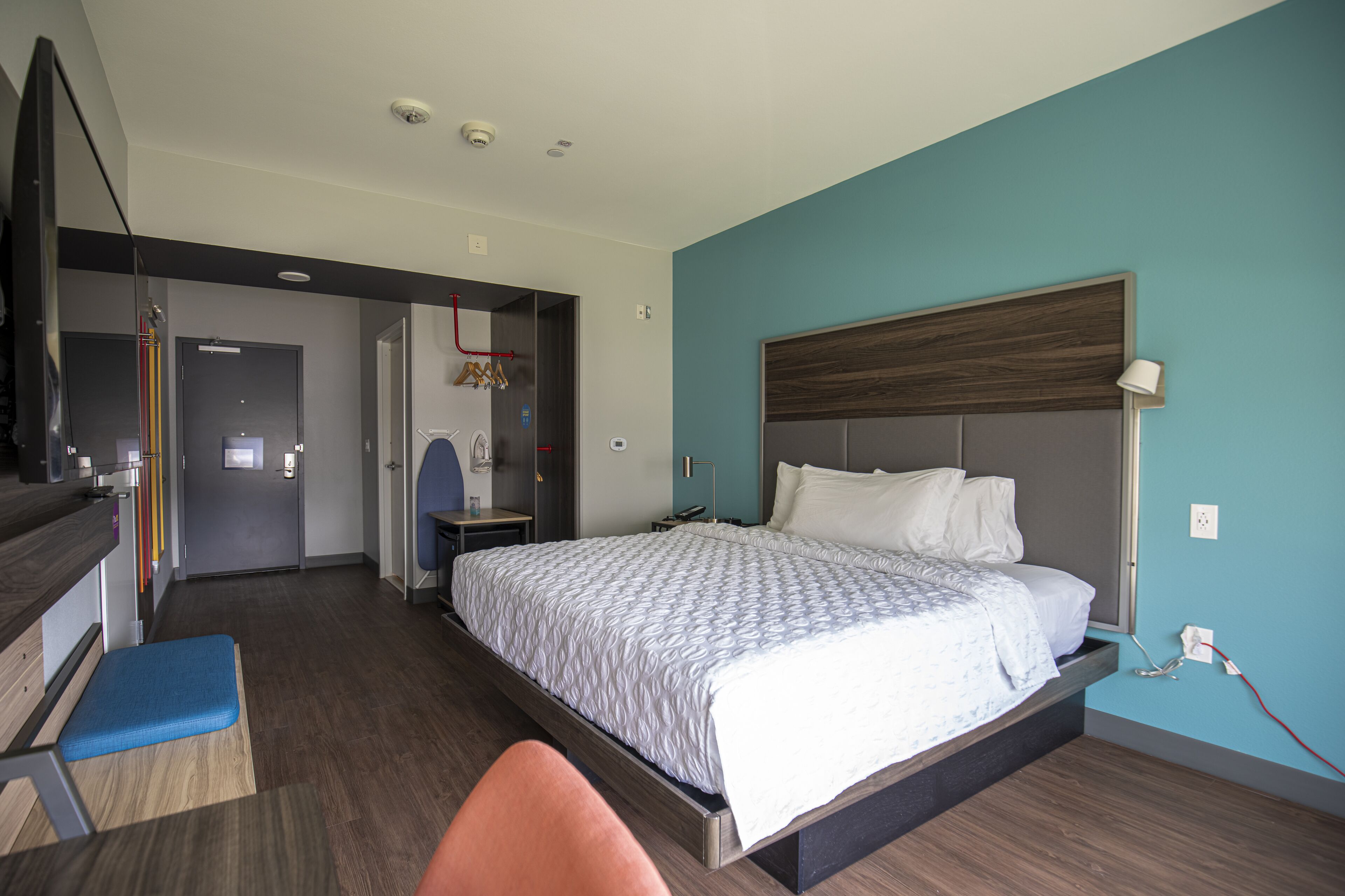 A modern hotel room with a large bed, a desk, and a chair.