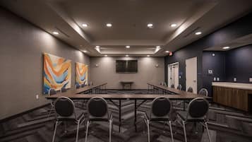 A conference room with a long table, chairs, a TV screen, and artwork on the walls.