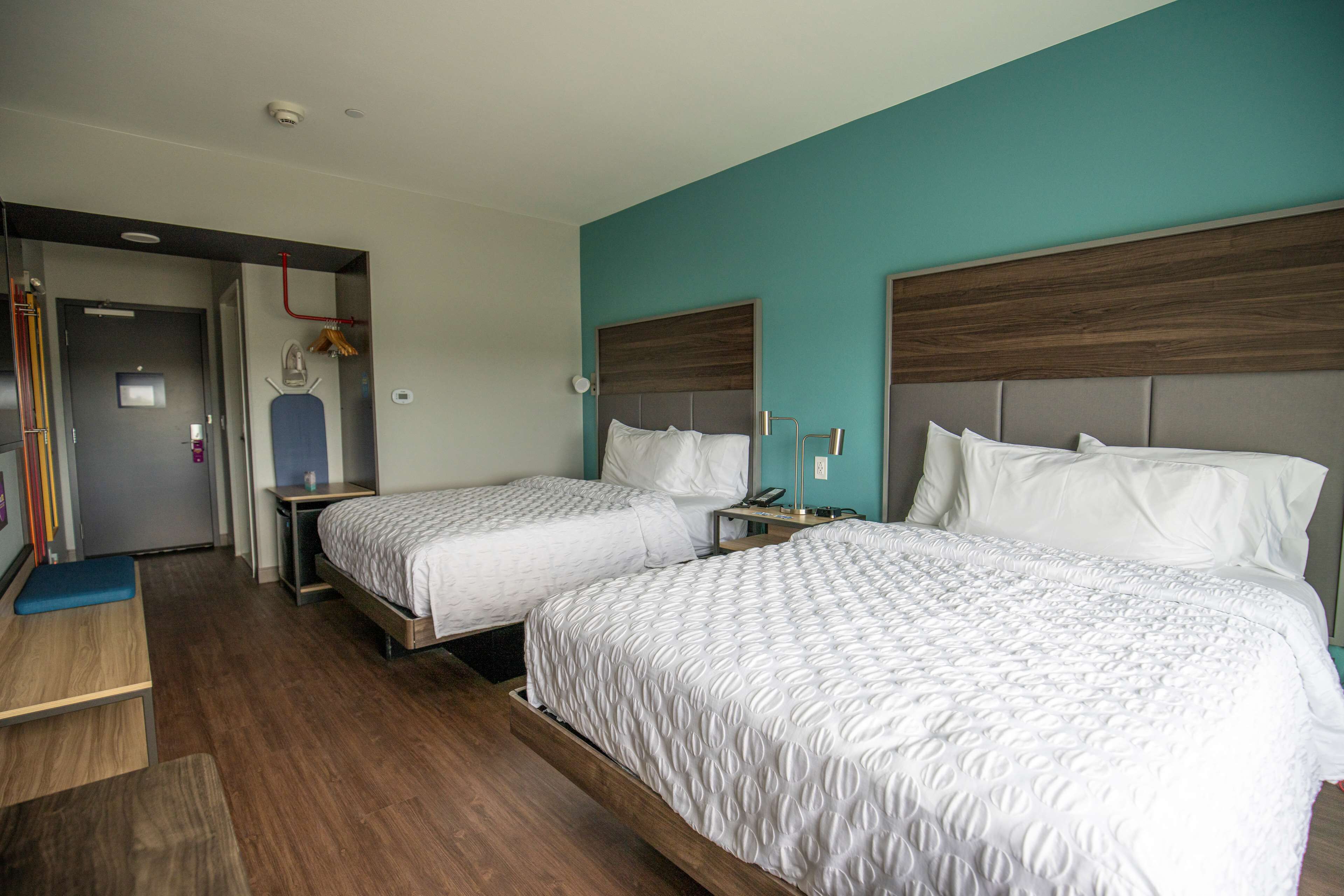 A hotel room with two beds, a desk, and a bathroom.