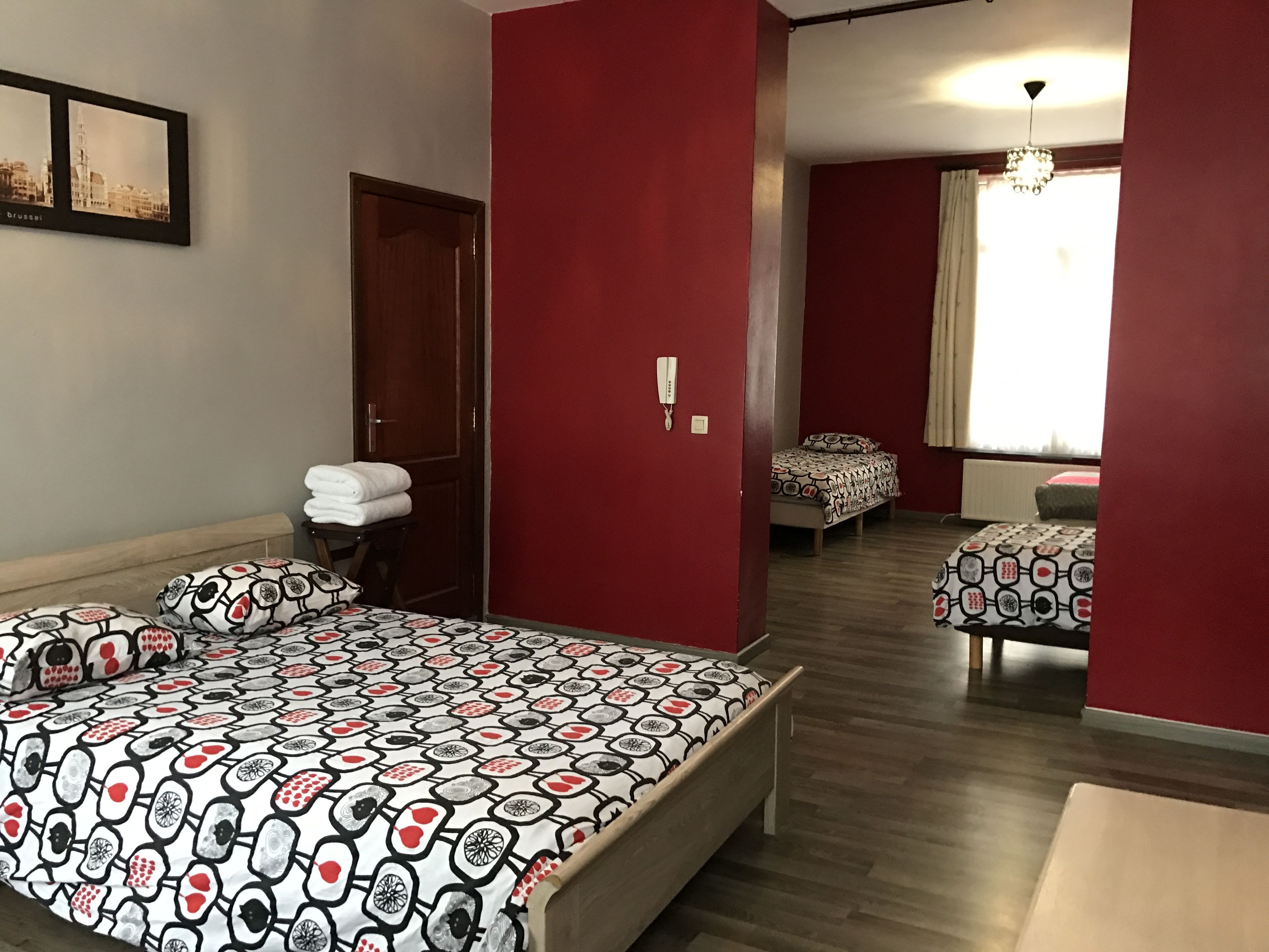A hotel room with a large bed, a desk, a chair, a wardrobe, and a bathroom visible through an open door.