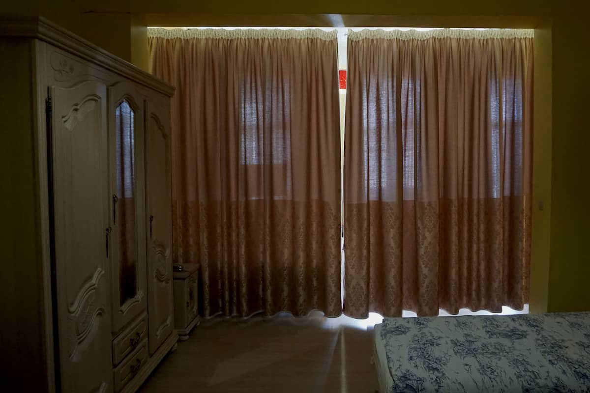A room with a bed, a wardrobe, and a door with a sign.