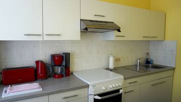 A kitchen with white cabinets, a Bosch coffee maker, a toaster, and a sink.