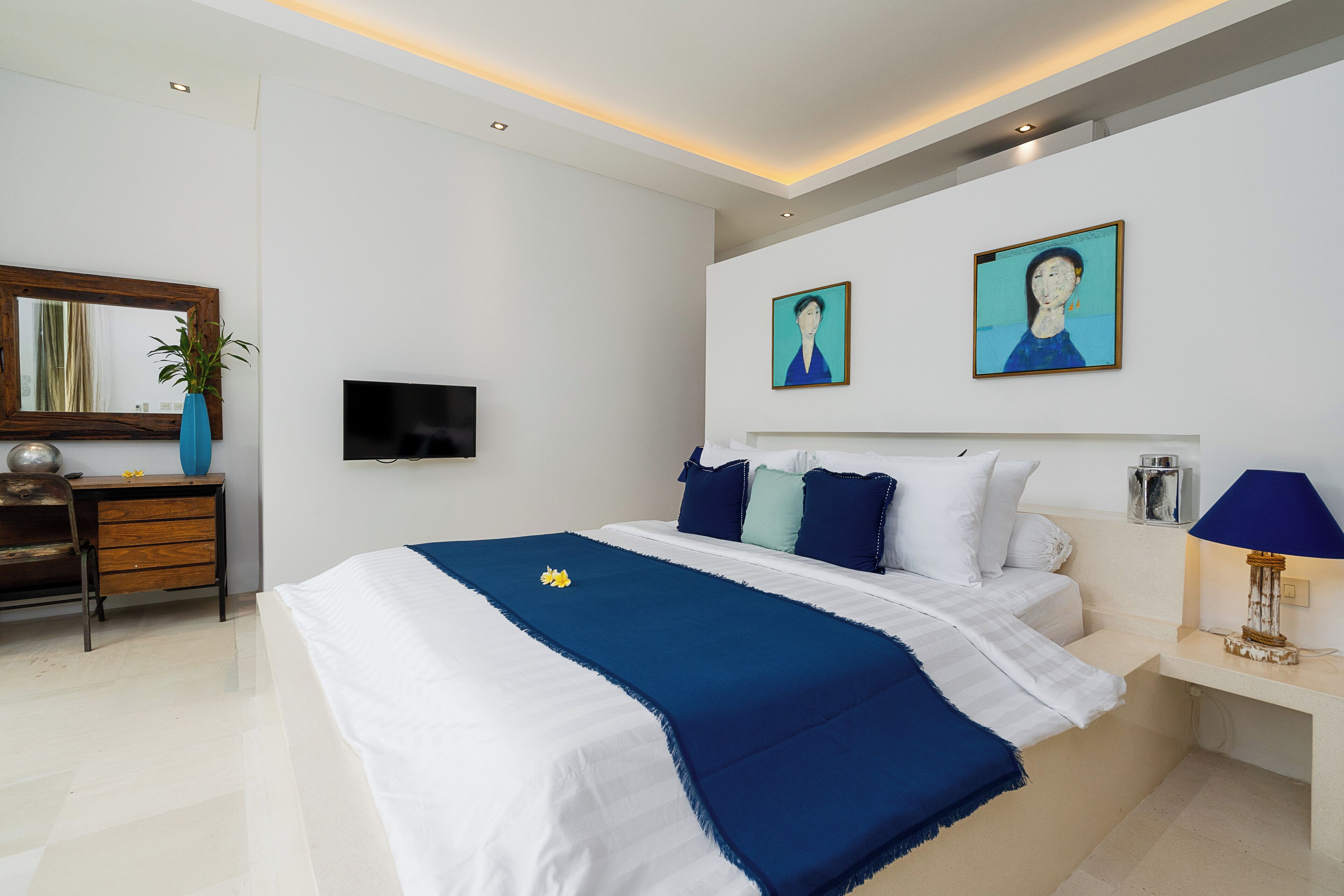 Een moderne slaapkamer met een groot bed, een bureau, een televisie en kunstwerken aan de muur.