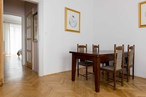 A dining area with a wooden table and chairs, a framed picture on the wall, and a door leading to another room.