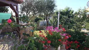 A garden with various plants and flowers, a stone wall, and a metal structure. - Apartment for 2 people and 2 children (Pula)