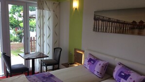 A bedroom with a bed, a chair, a small table, and a view of a garden through a glass door. - Apartment for 2 people and 2 children (Pula)