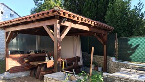 A wooden gazebo with a brick wall, a table, and chairs. - Apartment for 2 people and 2 children (Pula)